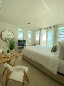 a bedroom with a large white bed and a mirror at Tres Palmas by La Cambija in Rincon