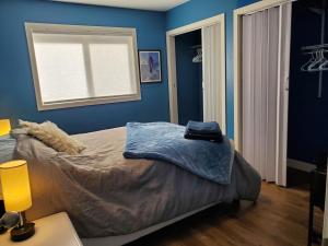 a bedroom with a bed with blue walls and a window at Saratoga beach cottage, private non-resort, easy beach access, 35mins Mt Washington in Oyster Bay