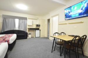 een hotelkamer met een tafel en een tv aan de muur bij Ben Chifley Motor Inn in Bathurst