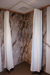 two white curtains in a bathroom with a stone wall at Mount Rumney Escapes Seaview House 2 - Eagle House in Mount Rumney