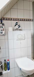 La salle de bains est pourvue de carrelage blanc, de toilettes et d'un lavabo. dans l'établissement FeWo-1-OG-links, à Böhl