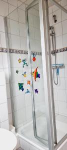 baño con ducha con pegatinas de pescado en la pared en FeWo-1-OG-links, en Böhl