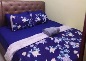 ein Bett mit einer lila Bettdecke und Kissen in der Unterkunft Homestay Asfa&Wazif in Arau