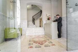 un homme debout à un comptoir dans un hall dans l'établissement Hotel San Lorenzo Boutique, à Valence