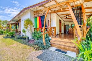 a home with a wooden porch with a colorful deck at Colibri Ecolodge 3 minutes walk to beach and town in Puerto Viejo