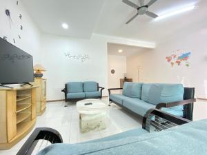 a living room with a blue couch and a tv at Taman Saikat IPOH comfortable HomeStay 12 Pax in Ipoh