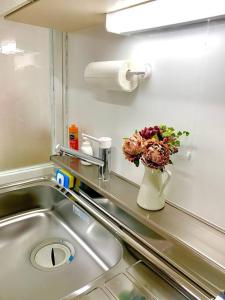 a vase of flowers on a counter next to a sink at COCO Nakameguro 202 in Tokyo