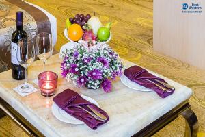 Best Western Chinatown Hotel في يانغون: طاولة مع قطعة مركزية من الفواكه والزهور وكؤوس النبيذ