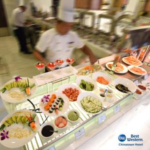 a chef in a kitchen with many plates of food at Best Western Chinatown Hotel in Yangon