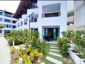 an exterior view of a white apartment building with plants at MAUÍ BEACH Tamandaré Flat Terreo in Tamandaré