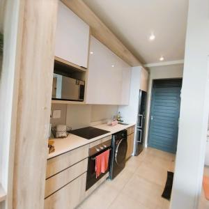 La cuisine est équipée de placards blancs et d'un lave-vaisselle. dans l'établissement Zimbali Lakes Boulevard Suites, Unit148, à Ballito