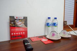 a table with two bottles of water and a remote control at RedDoorz near Stasiun Purwosari in Solo