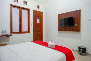 a bedroom with a bed and a flat screen tv at RedDoorz near Stasiun Purwosari in Solo