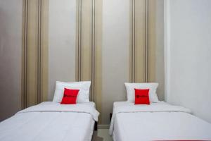 two beds with red pillows sitting next to each other at RedDoorz near Stasiun Purwosari in Solo