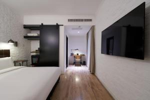 a bedroom with a bed and a tv on a wall at Yi Stack Hotel Beijing in Beijing