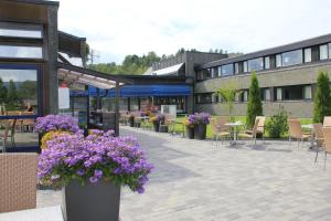 a patio with purple flowers and tables and chairs at Bø Hotel in Bø