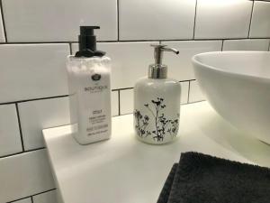 La salle de bains est pourvue de 2 bouteilles de savon et d'un lavabo. dans l'établissement Hamptons In Rye Green Cottage 3 Mins to Hot Springs!, à Rye 19 autres photos