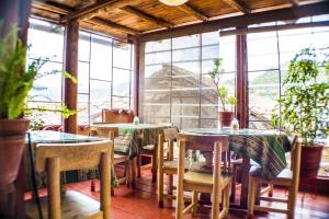a restaurant with tables and chairs in a room with windows at Samay Wasi Hostel in Cusco