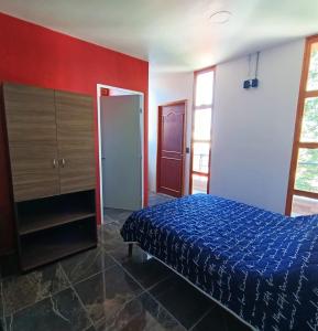 a bedroom with a blue bed and a red wall at Suite Aries in Tlatlauquitepec
