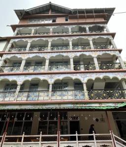 a building with balconies and a man standing on a balcony at Mount Khang Hotel in Lachen