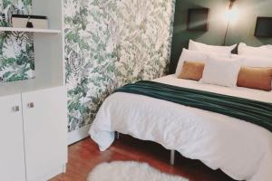 een slaapkamer met een bed met witte lakens en bloemenbehang bij T1 cocooning à l’Hôtel de Ville in Charleville-Mézières