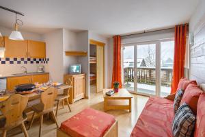 a living room with a couch and a table and a kitchen at Lagrange Vacances Les Pics d'Aran in Luchon