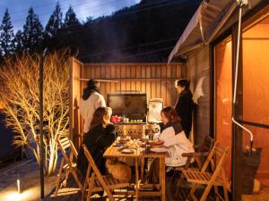 a group of people sitting around a table on a patio at Dot Glamping 富士山 in Fujikawaguchiko