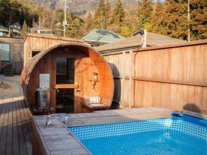 a wooden building with a swimming pool next to a house at Dot Glamping 富士山 in Fujikawaguchiko