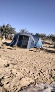 a tent sitting on a sandy beach with chairs at Hidden place in ‘Izbat Ţanāţī