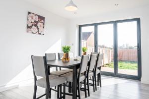 a dining room with a black table and chairs at Luxury Holiday Home Free Parking By the Beach in Warden