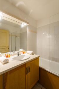 a bathroom with a sink and a bath tub at Lagrange Vacances Les Pics d'Aran in Luchon