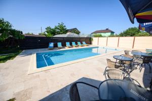 a swimming pool with chairs and a table and a patio at Vila Maia in Corbu