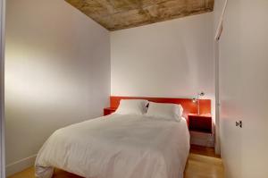1 dormitorio con cama blanca y cabecero rojo en Les Immeubles Charlevoix - Le 760204 en Quebec
