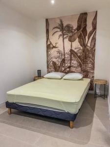 a bed in a room with a painting on the wall at La villa canne à sucre in Sainte-Suzanne