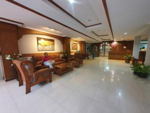 a woman sitting on a couch in a lobby at PN Inn Hotel Pattaya in Pattaya South