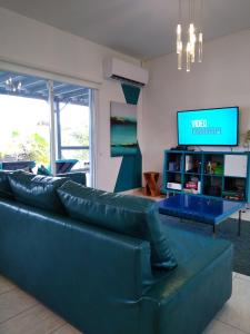 a living room with a blue couch and a tv at Turquoise Villa in Paradijs