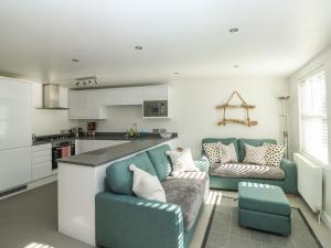 a living room with a blue couch and a kitchen at 1 Kents Mews in Torquay