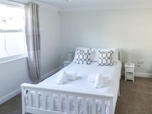 a white bedroom with a white bed and a window at 1 Kents Mews in Torquay