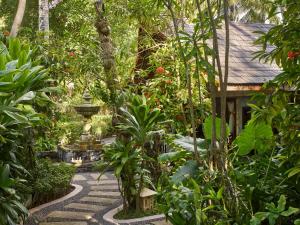 a path in a garden with trees and a house at Sun Island Resort & Spa in Maamigili
