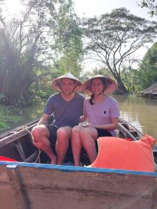 Ein Mann und eine Frau sitzen auf einem Boot auf dem Wasser in der Unterkunft Green Sunshine in Cần Thơ