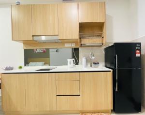 a kitchen with wooden cabinets and a black refrigerator at Melaka Town Homestay Bali Residences Apartment in Melaka