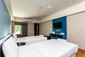 Solace at Srinakarin Hotel في بانغنا: غرفة فندقية بسريرين وتلفزيون