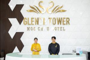 木州的住宿－Glenda Tower Moc Chau Hotel，两个妇女站在桌子前,有标志