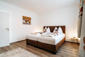 a bedroom with a bed with white walls and wooden floors at Gemütliche Wohnung im Zentrum in Zeltweg