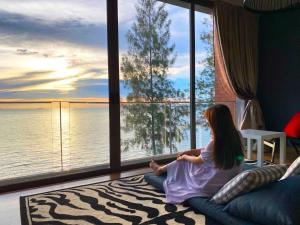a little girl sitting on a couch looking out at the water at Sandbox frontbeach villa4 in Bang Lamung