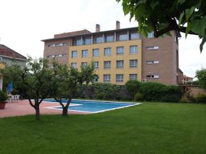 a building with a swimming pool in front of a building at Aparthotel Solé in La Pobla de Segur