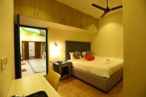 a bedroom with a bed and a table and a mirror at Zingle Stay Airport Hotel in Chennai