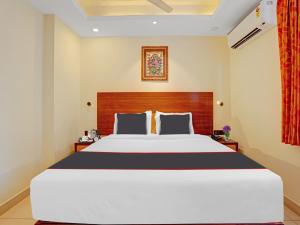 a bedroom with a large white bed with a wooden headboard at Pallava Rajadhani in Trivandrum