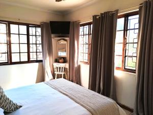 1 dormitorio con 1 cama y 2 ventanas en Old Mill Guest House en Durban