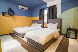 a hotel room with two beds and a tv at The Cave By Cactus Hotel Skudai in Skudai
